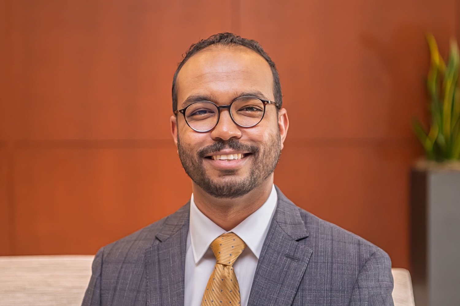 Smiling man in a suit with glasses.