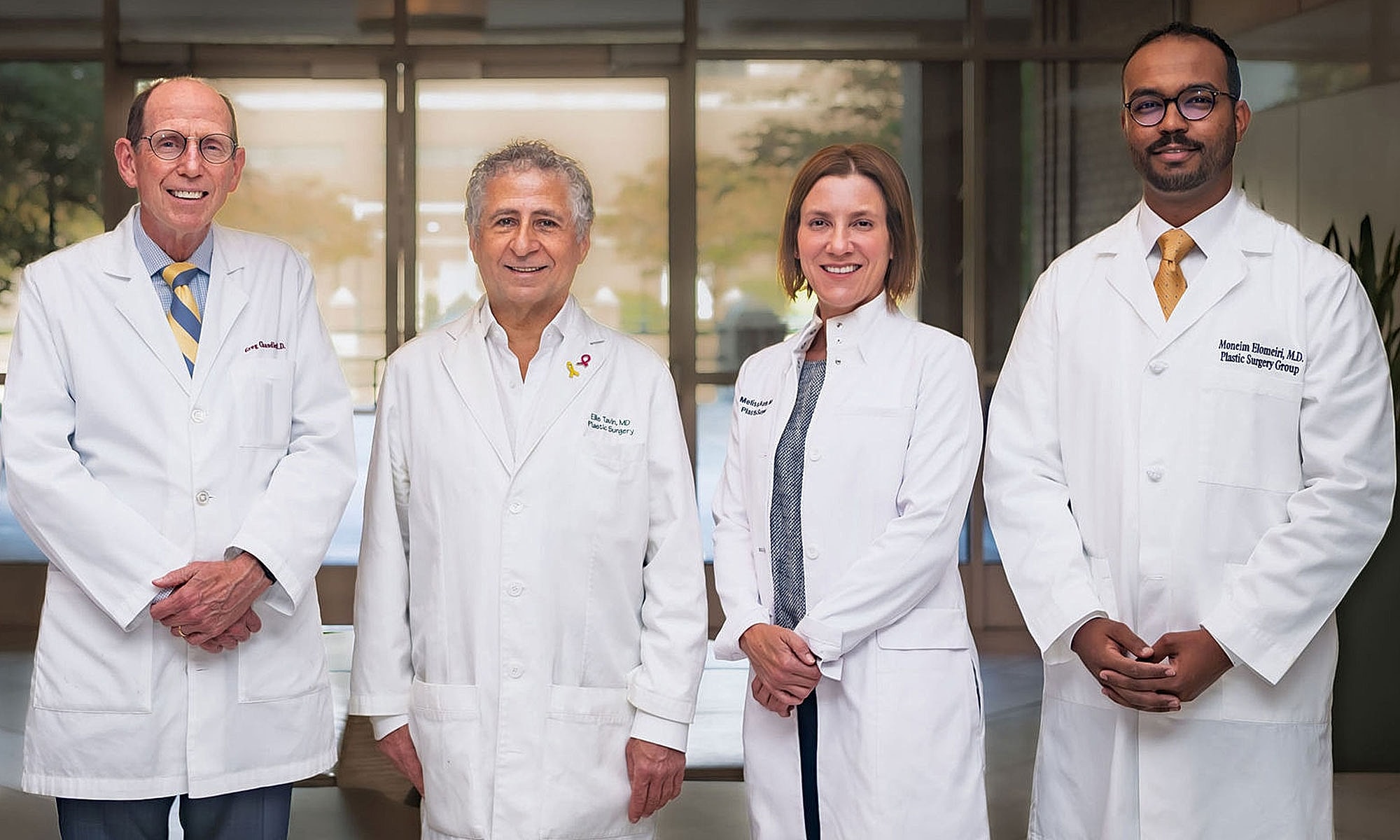 Four doctors in white coats posing together.