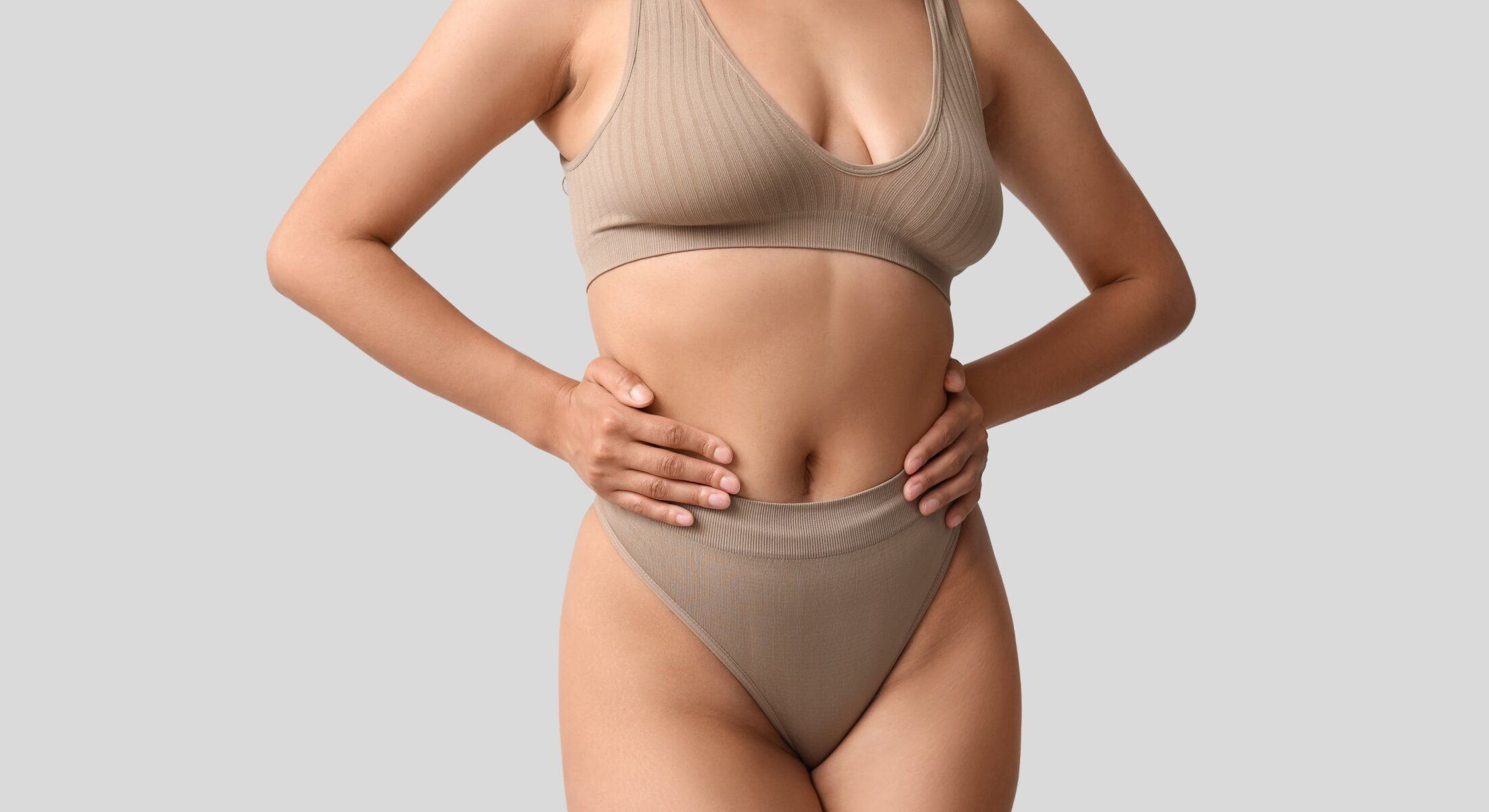 Model in beige lingerie, hands on waist.